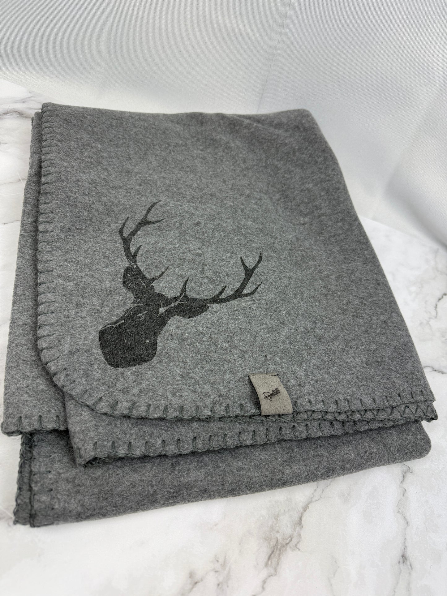 Kuschelige graue Fleece-Decke mit Hirschmotiv, gefaltet auf hellem Untergrund, weich und gemütlich, 130x170 cm
