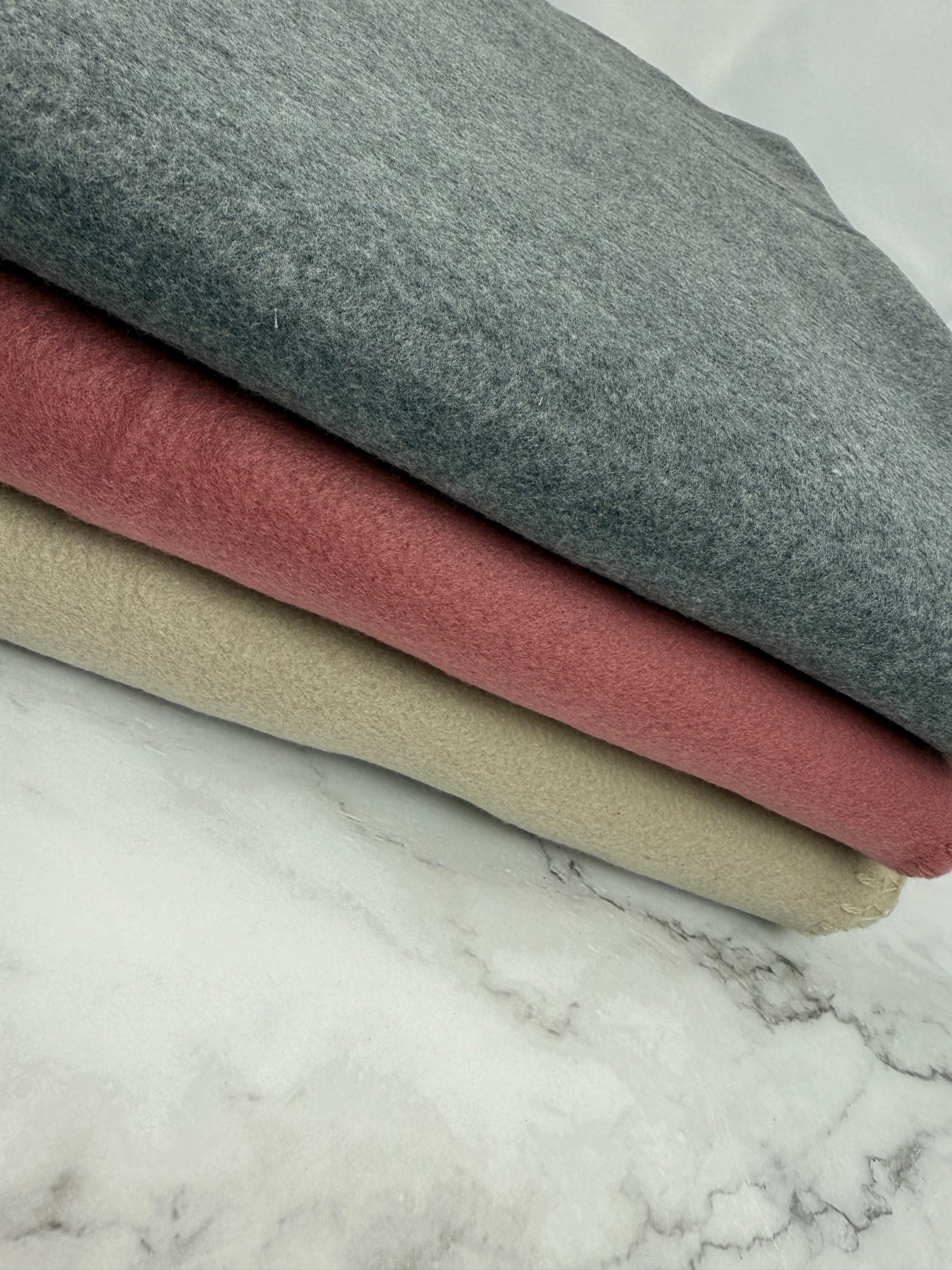 Gefaltete Fleece-Decke in Beige mit Schriftzug „Hoamt is koa Ort, sondern a Gfui“, kuschelig und dekorativ