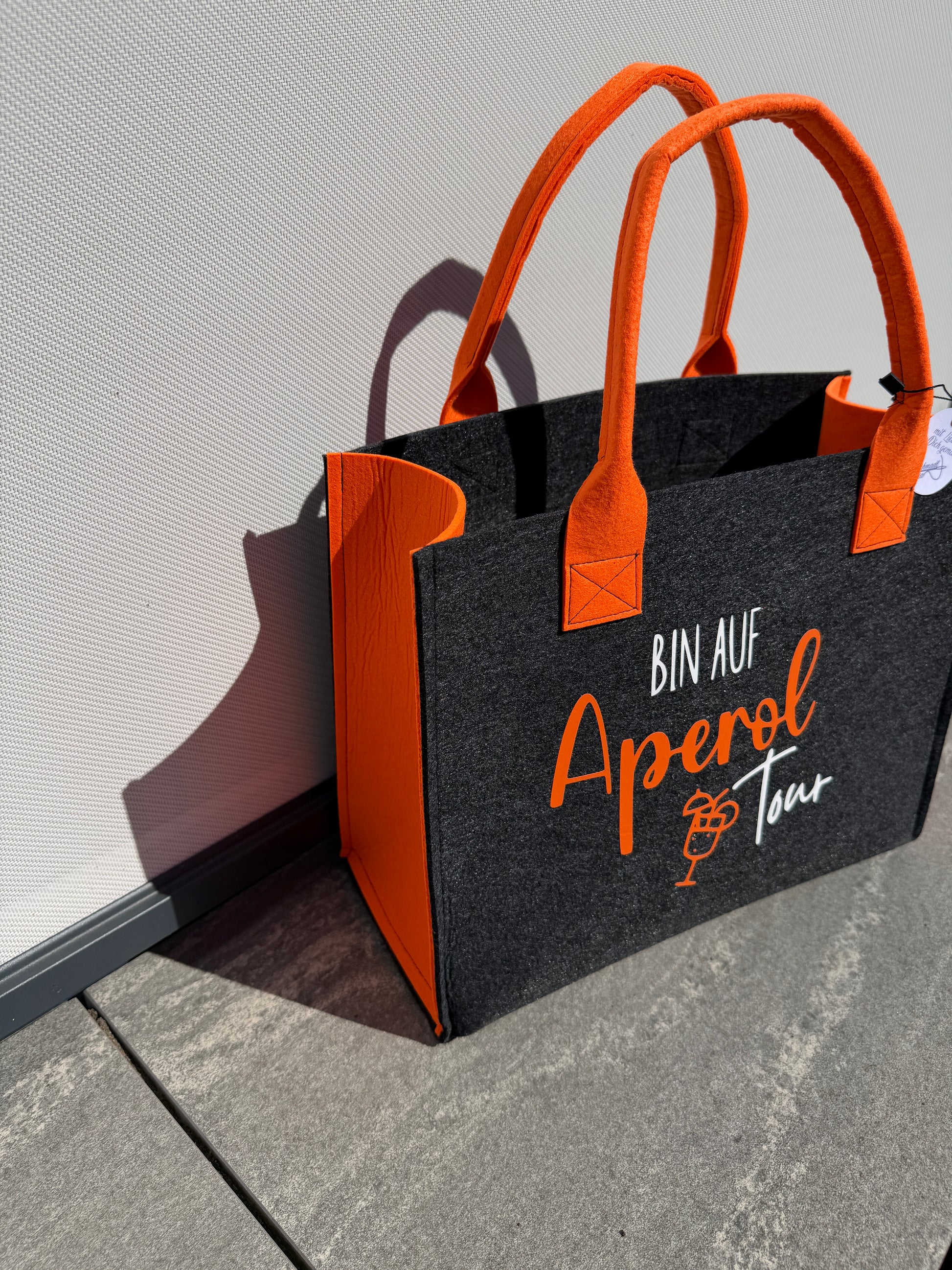 Handgefertigte anthrazitfarbene Filztasche mit orangenen Tragegriffen und dem Spruch „Bin auf Aperol Tour“ – stylische Shopper-Tasche für Sommer, Freizeit und Urlaub.
